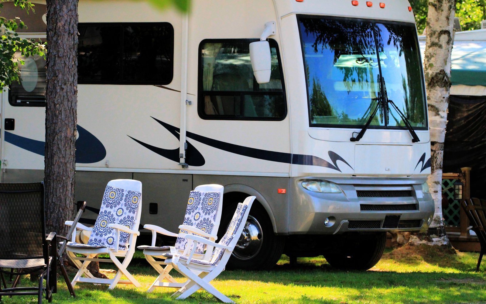 Picture of a parked RV with two lawn chairs nearby
