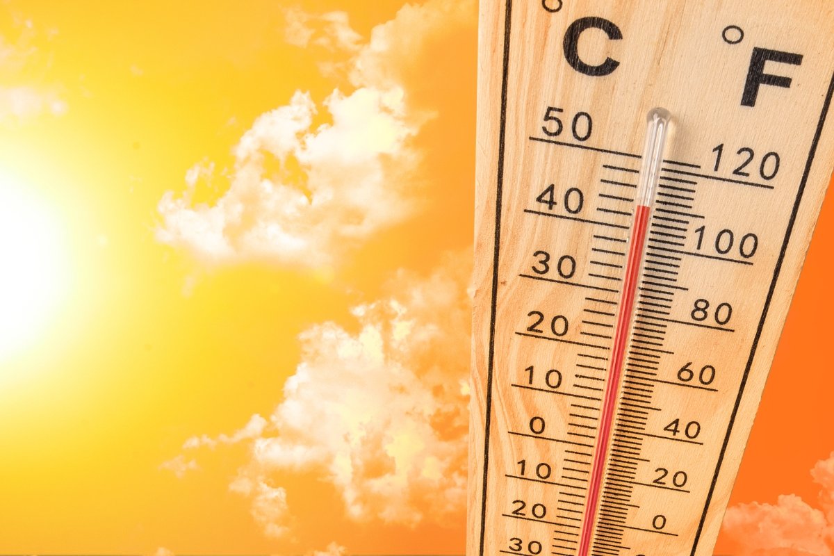 Bright yellow-orange sky with clouds (in the distance) with a wooden thermometer showing high temperature- over 100 degrees F.