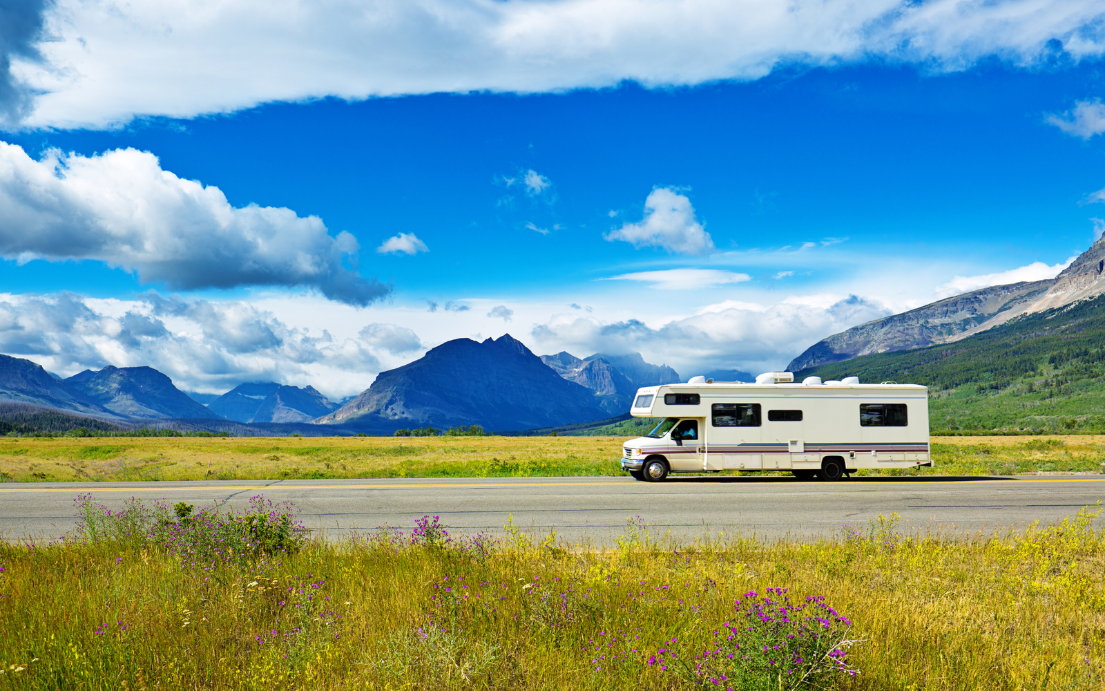 RV driving down road with mountains in background
