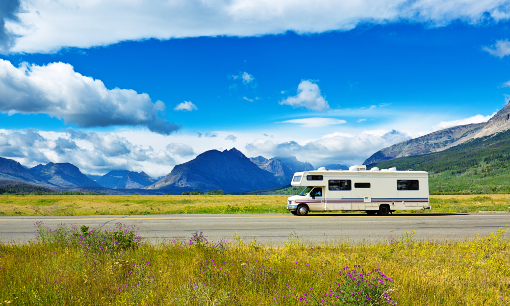 RV driving down road with mountains in background