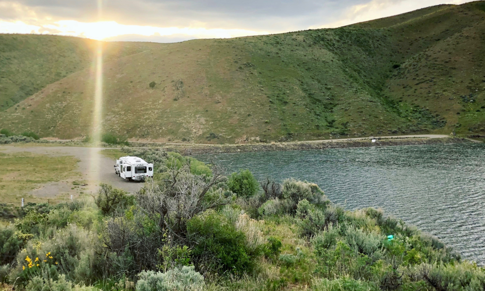 RV driving up to hills and lake/pond.